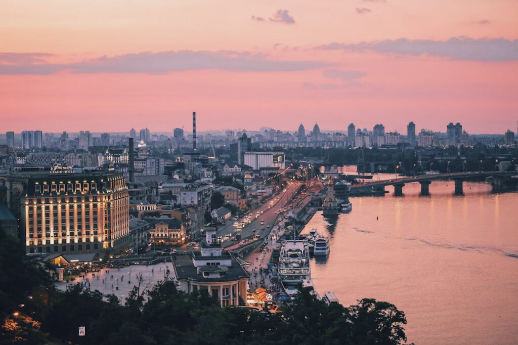 A beautiful view of the Kyiv cityscape at dusk, featuring the waterfront and lively urban skyline.